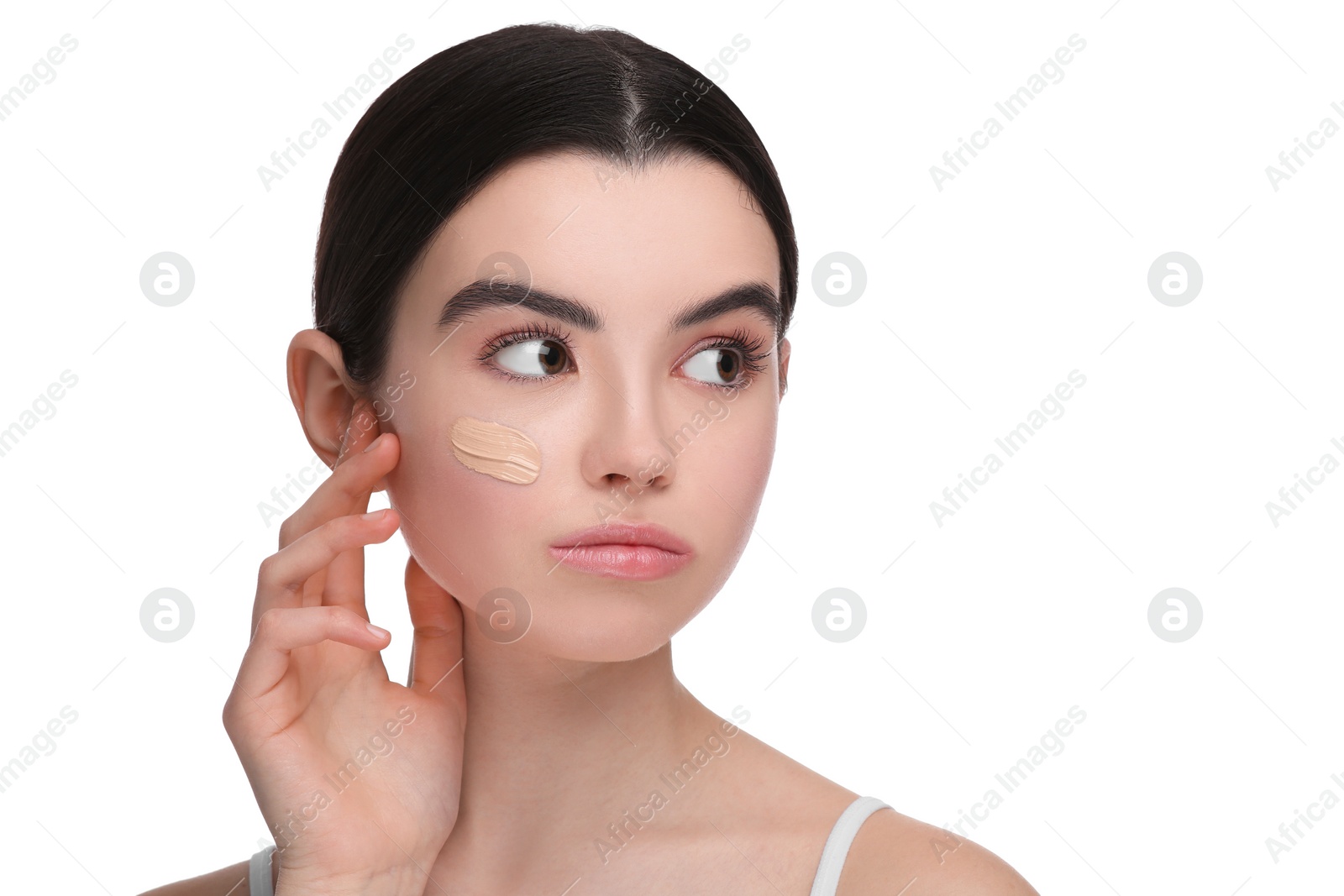 Photo of Teenage girl with swatch of foundation on face against white background