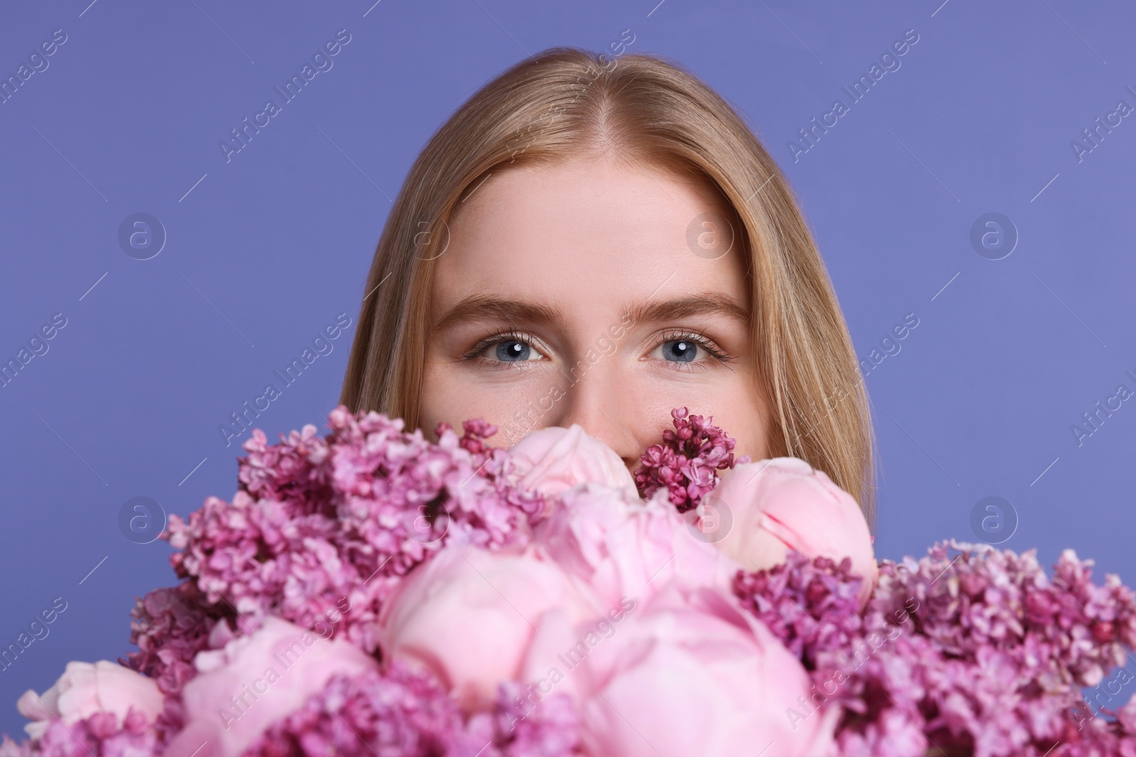 Photo of Woman with bouquet of spring flowers on purple background, closeup