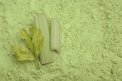 Photo of Fresh stalks on natural celery powder, above view. Space for text