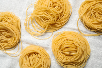 Photo of Capellini pasta on white tablecloth, flat lay