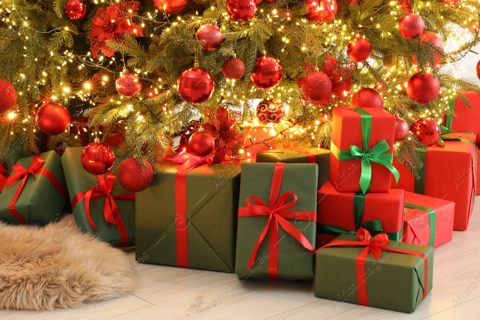 Photo of Many gift boxes under decorated Christmas tree indoors