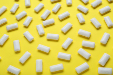 Photo of Tasty white chewing gums on yellow background, flat lay