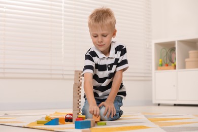 Photo of Cute little boy playing with wooden toys indoors