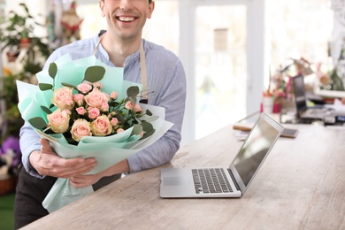Photo of Male florist holding bouquet flowers at workplace