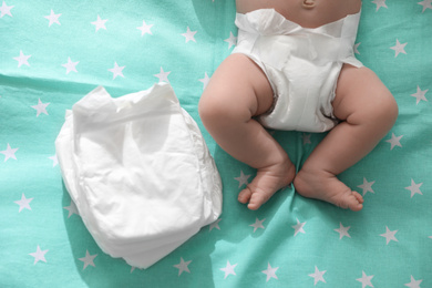 Photo of Cute little baby in diaper lying on bed, top view