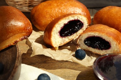 Photo of Delicious baked patties with jam and blueberries on wooden table, closeup
