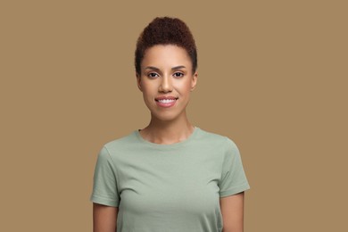 Portrait of beautiful young woman on light brown background