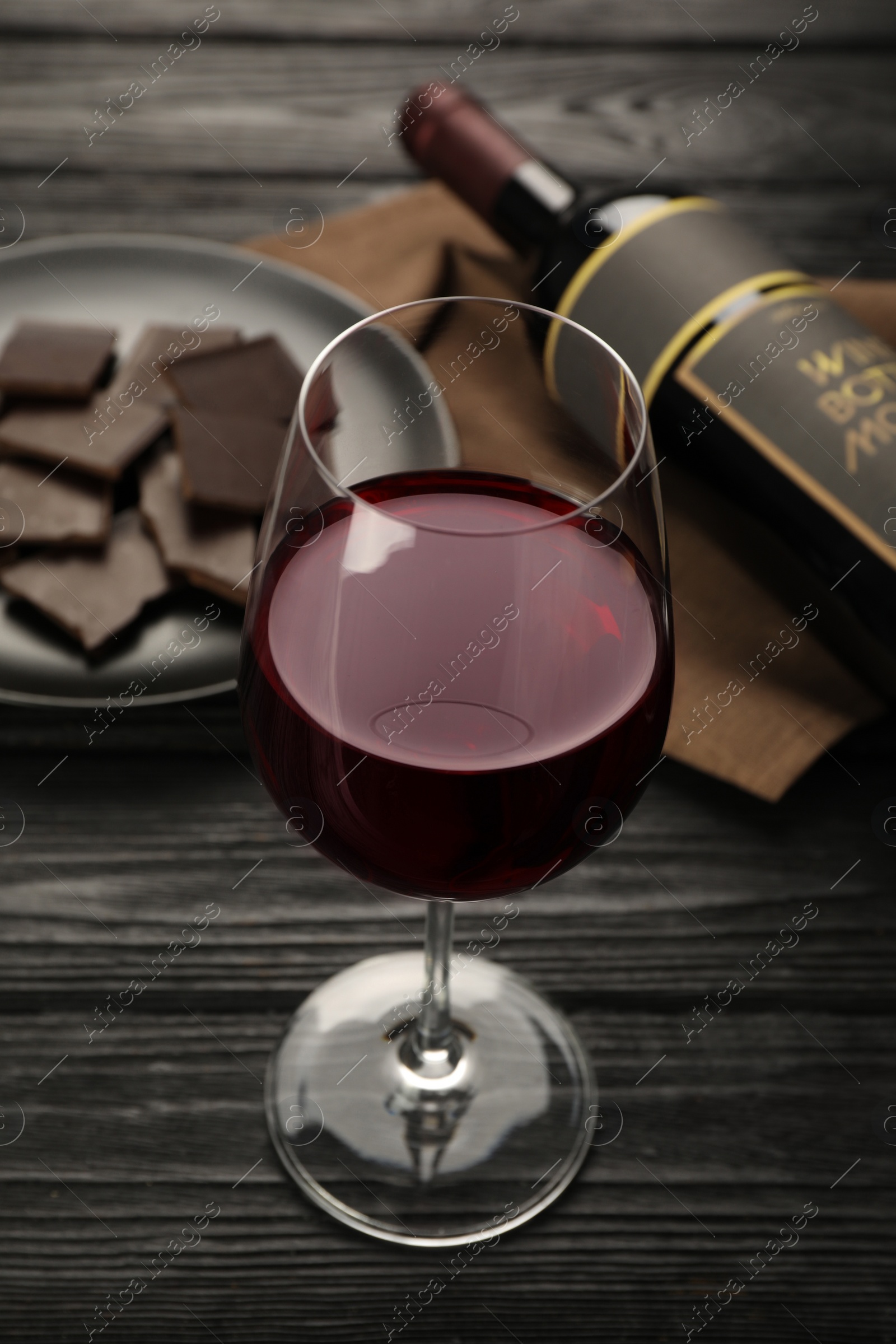 Photo of Tasty red wine and chocolate on black wooden table