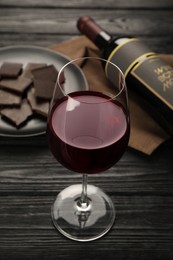 Tasty red wine and chocolate on black wooden table