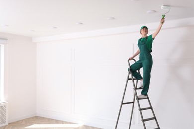 Worker painting ceiling with white dye indoors, space for text