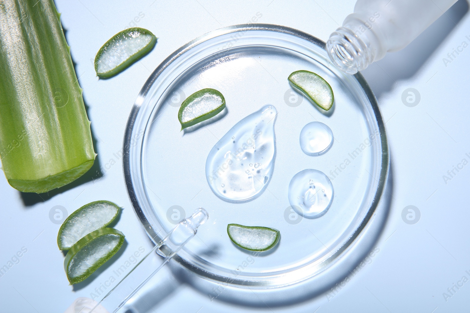 Photo of Cut aloe vera, bottle and drops of cosmetic gel on light blue background, flat lay