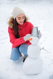 Young woman making snowman outdoors on winter day