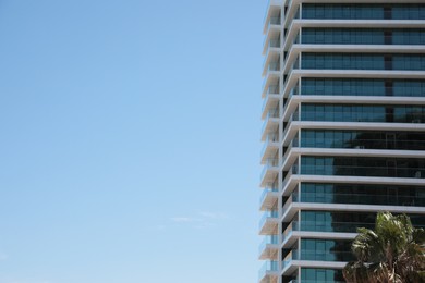 Photo of Exterior of residential building with balconies against blue sky, low angle view. Space for text