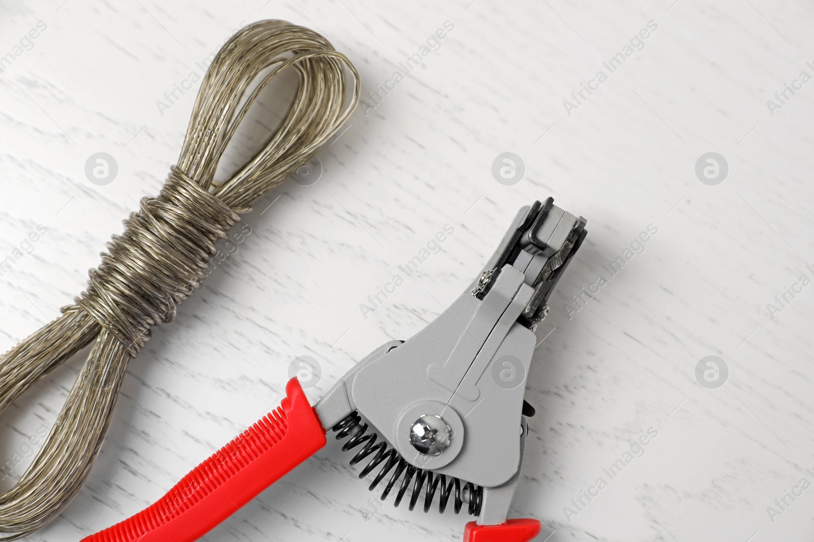 Photo of Professional cutters and wire on white wooden table, flat lay