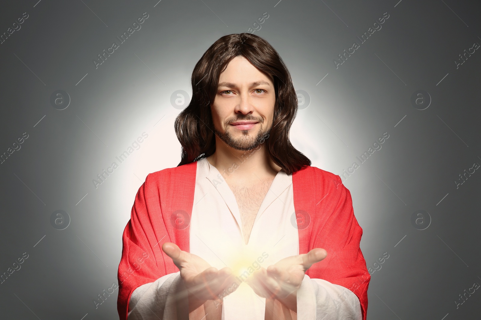Image of Jesus Christ on grey background. Miraculous light in hands