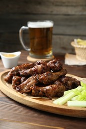 Delicious chicken wings served with beer on wooden table