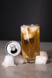 Photo of Tasty energy drink with ice cubes in glass and aluminium can on grey table