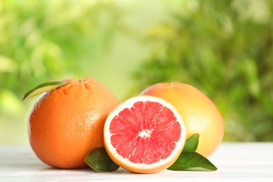 Photo of Yummy grapefruits on wooden table against blurred background