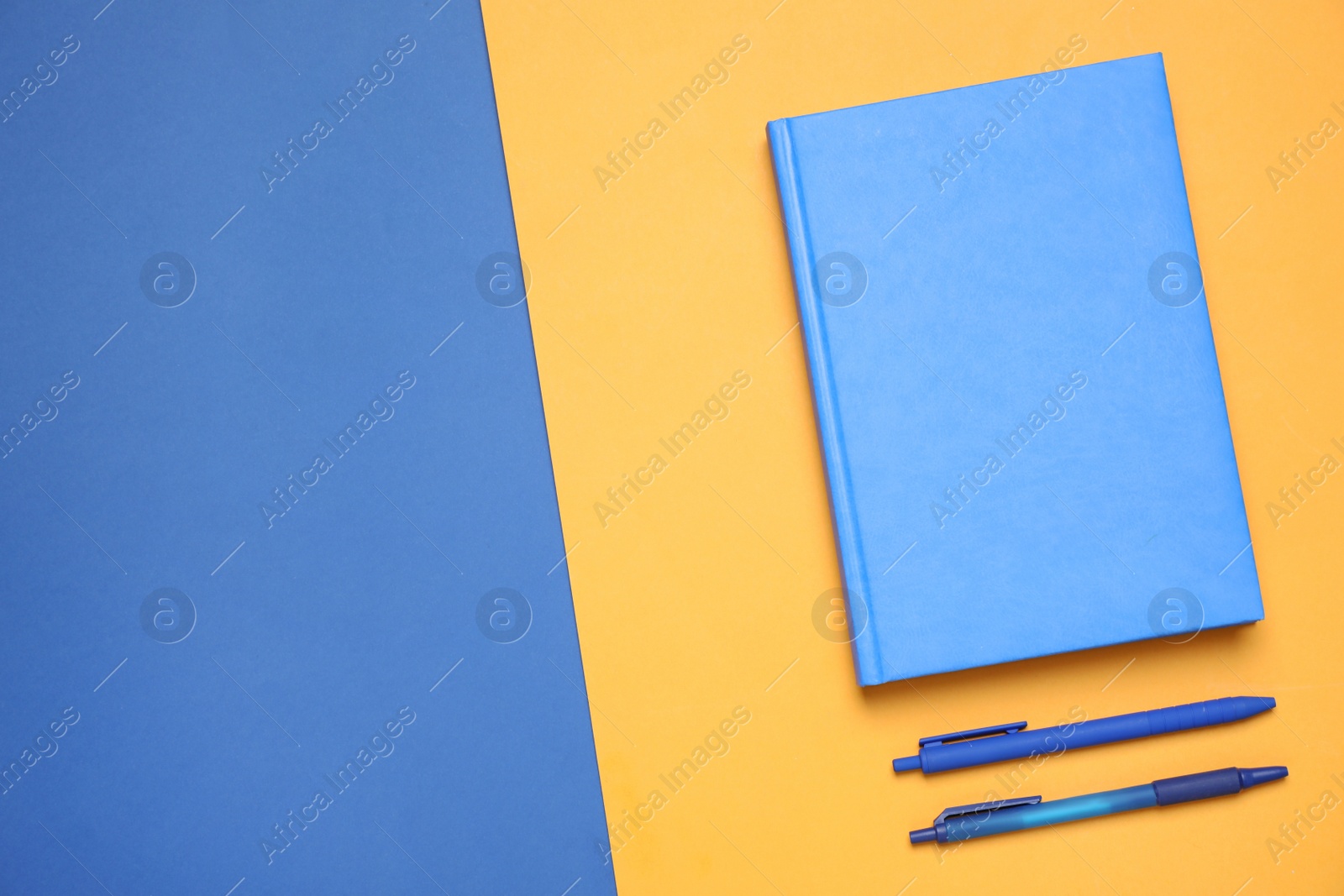 Photo of Stylish notebook and pens on color background, flat lay. Space for text