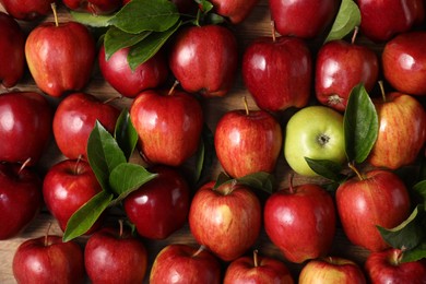 Photo of Fresh ripe apples with leaves on wooden table, flat lay