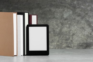 Portable e-book reader and many hardcover books on white textured table, space for text