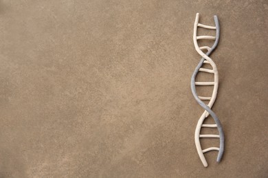 Photo of DNA molecule model made of colorful plasticine on brown background, top view. Space for text
