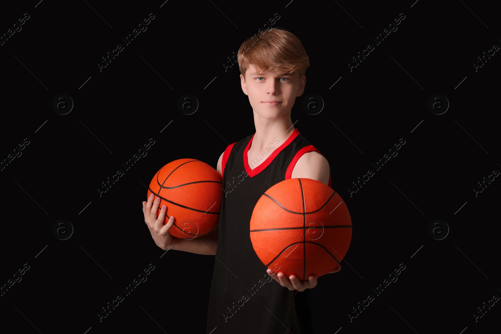 Photo of Teenage boy with basketball balls on black background