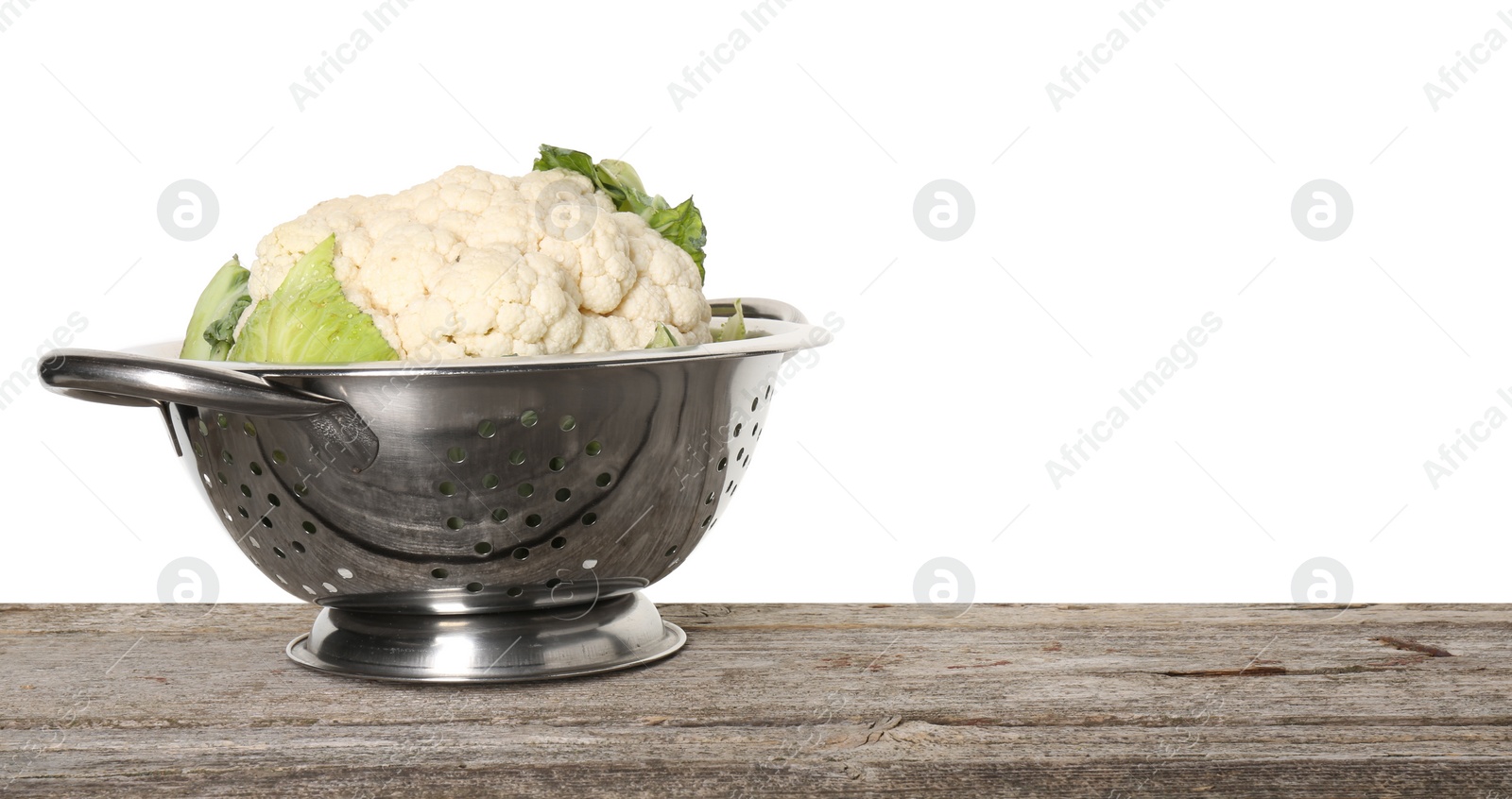 Photo of Metal colander with cauliflower on wooden table against white background, space for text