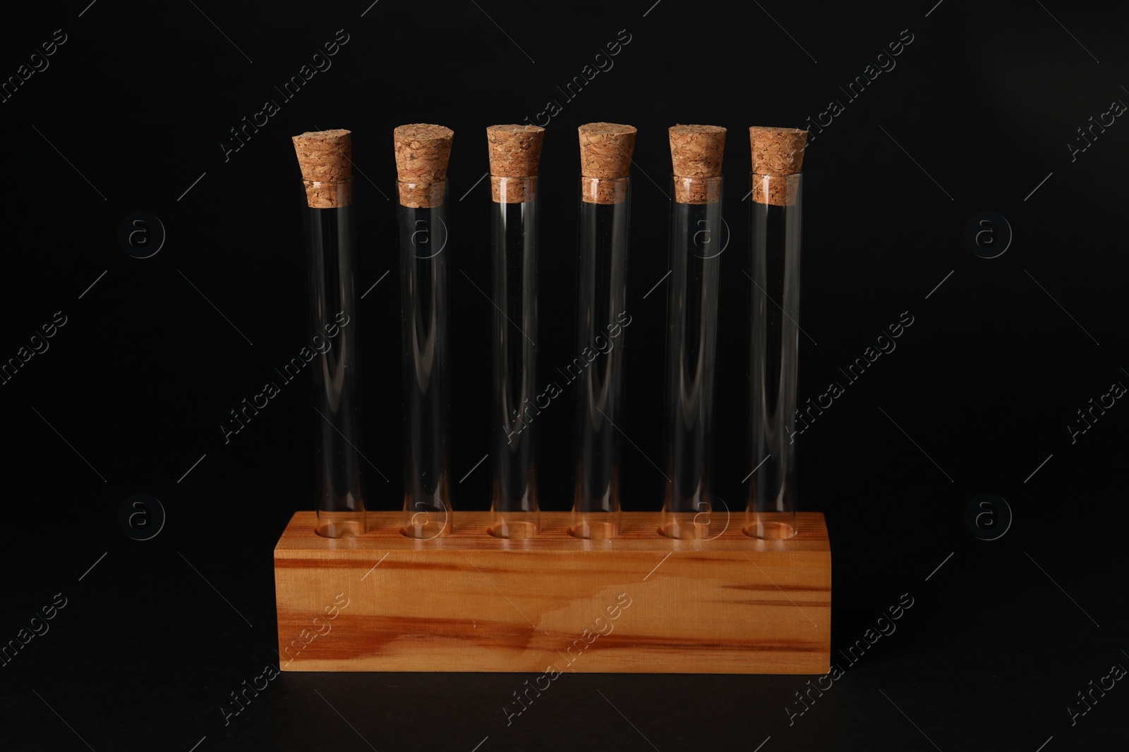 Photo of Test tubes in wooden stand on black background. Laboratory glassware