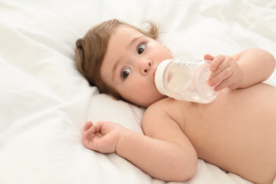 Cute little baby with bottle on bed