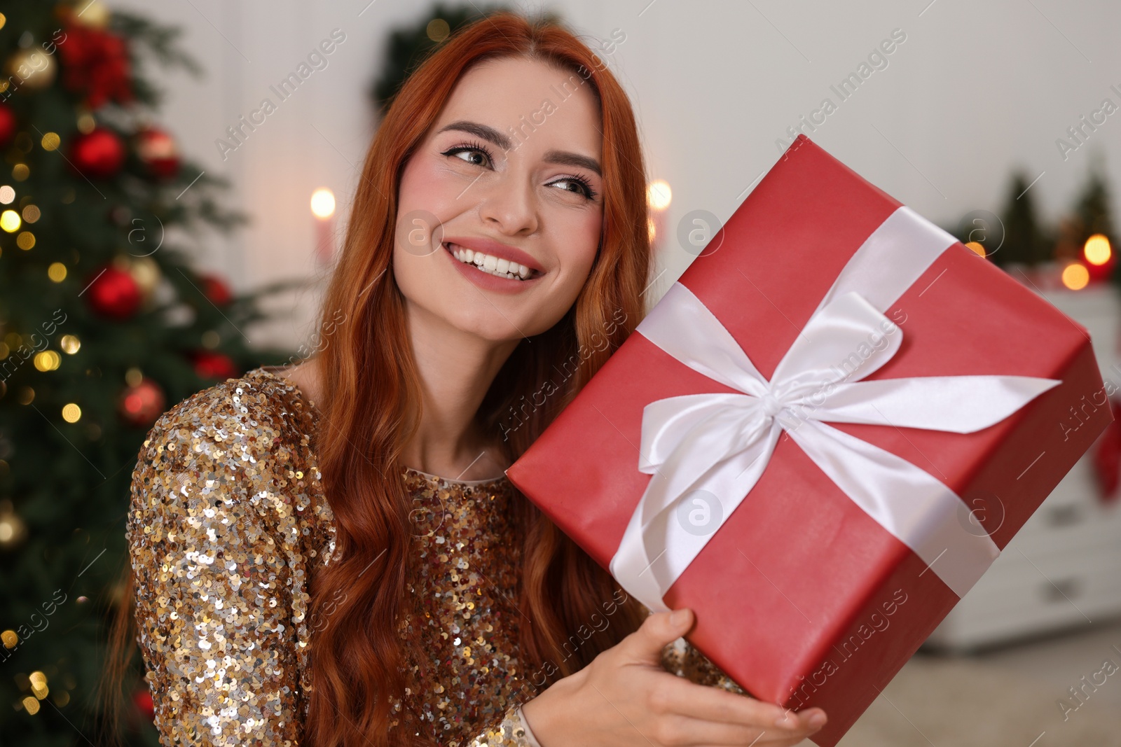 Photo of Happy young woman with Christmas gift at home