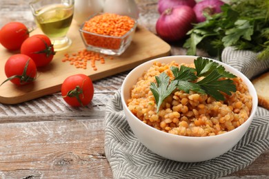 Photo of Delicious red lentils with parsley in bowl on wooden table, space for text