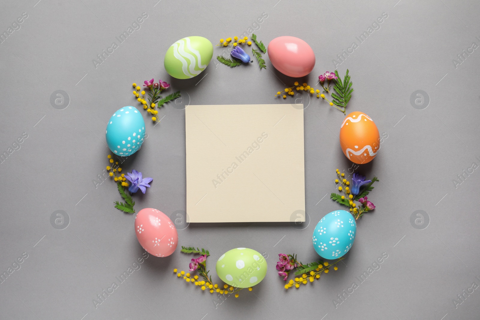 Photo of Flat lay composition of painted Easter eggs and blank card on color background, space for text