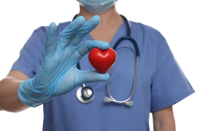 Photo of Doctor wearing light blue medical glove holding decorative heart on white background, closeup