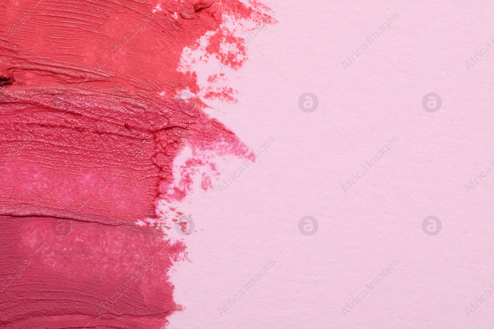 Photo of Smears of beautiful lipsticks on pink background, top view. Space for text