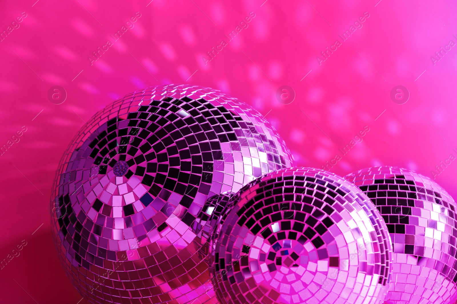 Photo of Many shiny disco balls near color wall, toned in pink