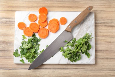 Board with sharp knife and cut products on wooden background, flat lay