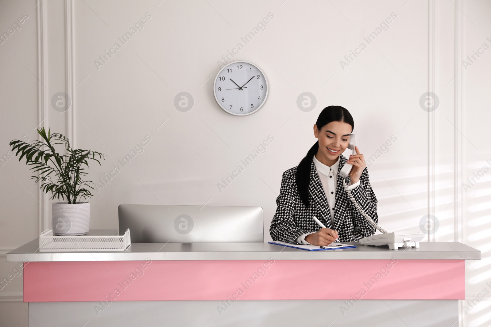 Photo of Receptionist talking on phone at countertop in office