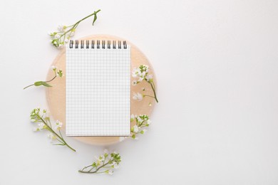 Guest list. Notebook and beautiful spring tree blossoms on white background, flat lay. Space for text