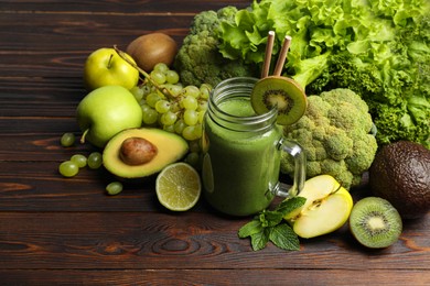 Photo of Green smoothie in mason jar and fresh ingredients on wooden table. Space for text