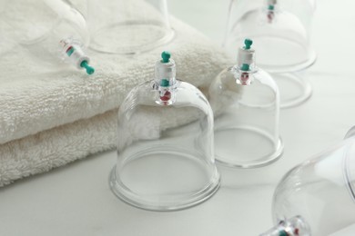 Photo of Plastic cups and towel on white marble table, closeup. Cupping therapy