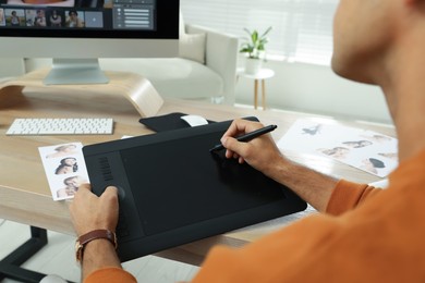 Photo of Professional retoucher working with graphic tablet at desk in office, closeup
