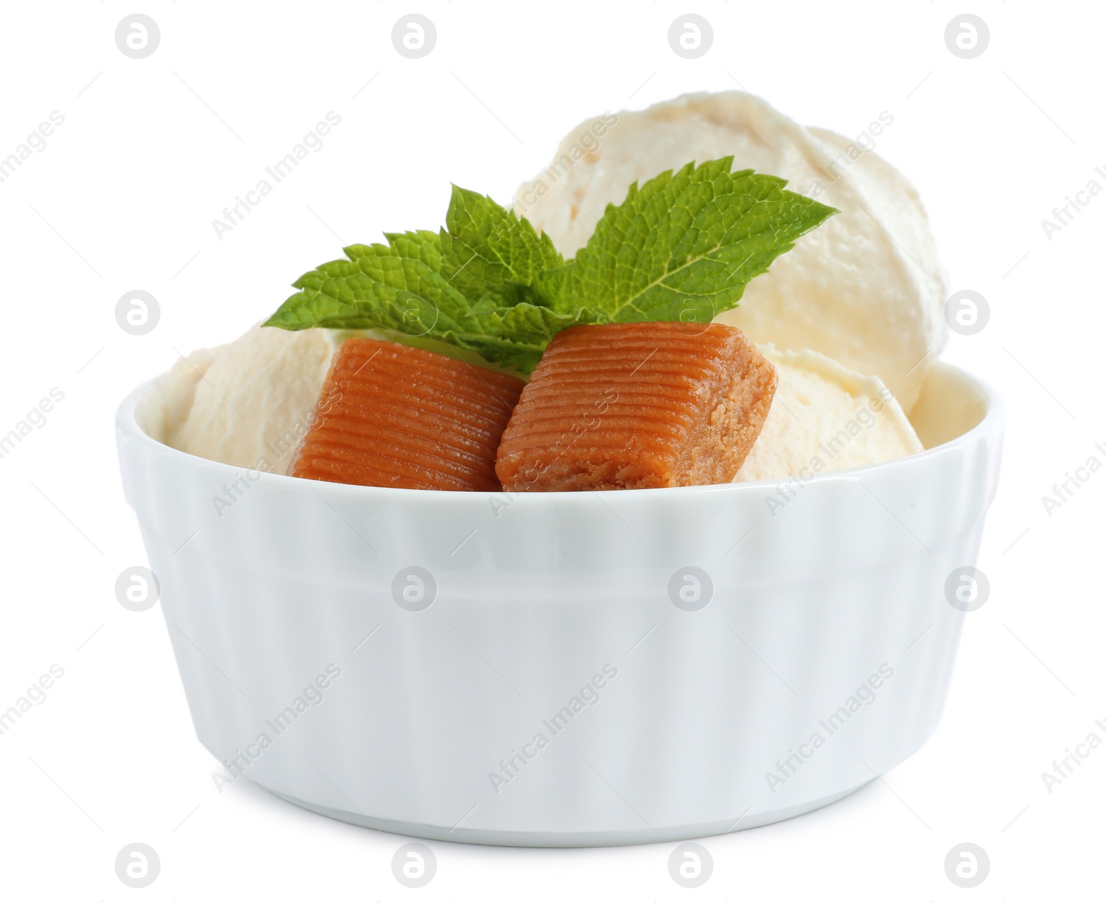 Photo of Bowl of delicious ice cream with caramel candies and mint on white background