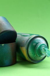 Photo of Spray paint can with caps on green background, closeup