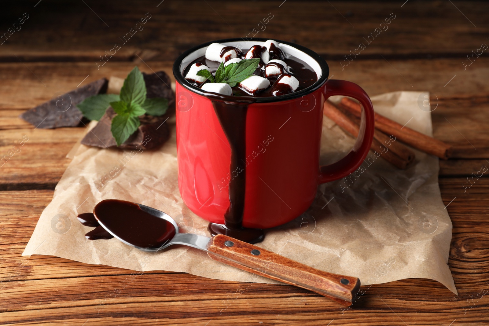 Photo of Mug of delicious hot chocolate with marshmallows and fresh mint served on wooden table