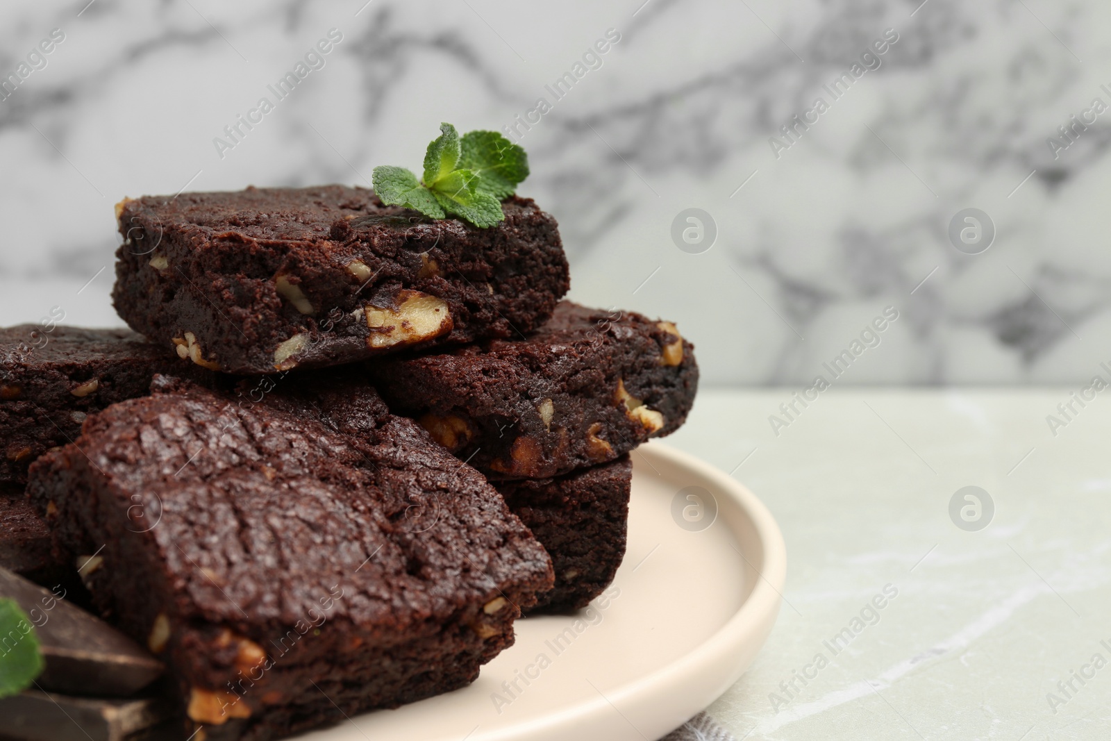 Photo of Delicious chocolate brownies with nuts and fresh mint on light grey table, closeup. Space for text