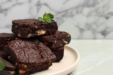 Photo of Delicious chocolate brownies with nuts and fresh mint on light grey table, closeup. Space for text