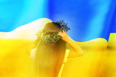 Double exposure of cute little girl wearing flower wreath in field and Ukrainian flag 