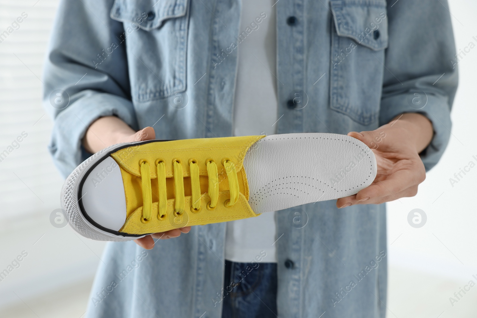 Photo of Woman putting orthopedic insole into shoe indoors, closeup. Foot care