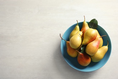 Photo of Plate with ripe pears on light background, top view. Space for text